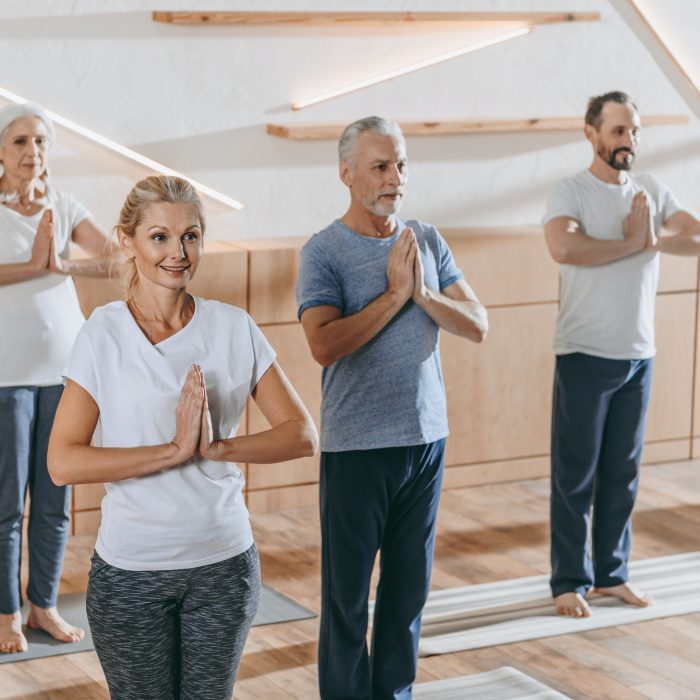 senior group of people with instructor practicing yoga at training class